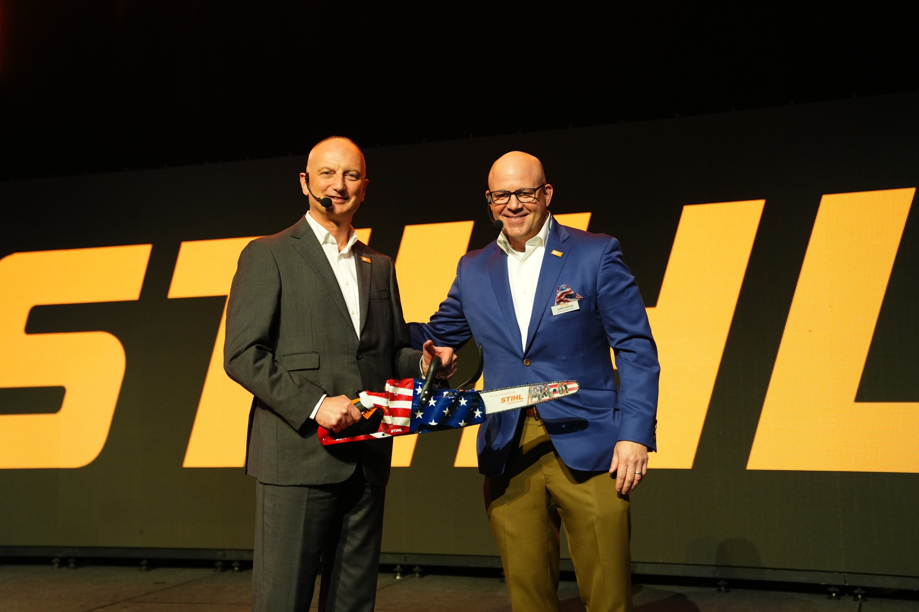 Dr. Nikolas Stihl (vlevo) a Chris Keffer, generální ředitel společnosti STIHL Inc. v USA, představují jubilejní pilu s americkou vlajkou.